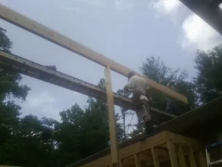 Carpenter setting a ridge beam over a new addition frame — Ice Dam Removal by Roofing Brothers in Brookhaven