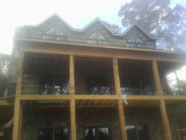 Dormers and porch framing on a large log home under construction — Roof Coating work by our crew in Brookhaven
